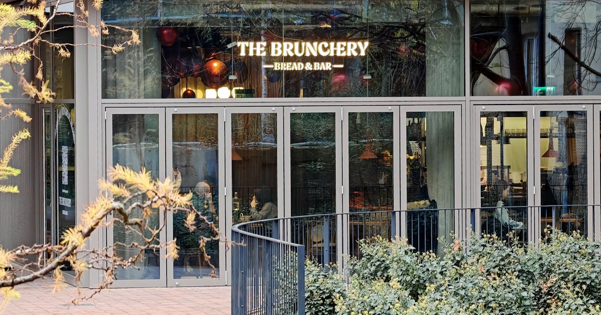 Witryna lokalu od strony patio, z podświetlonym szyldem The Brunchery